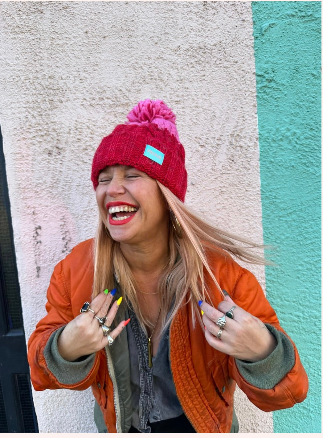 Silky lined pom pom hat in red and pink with proud logo