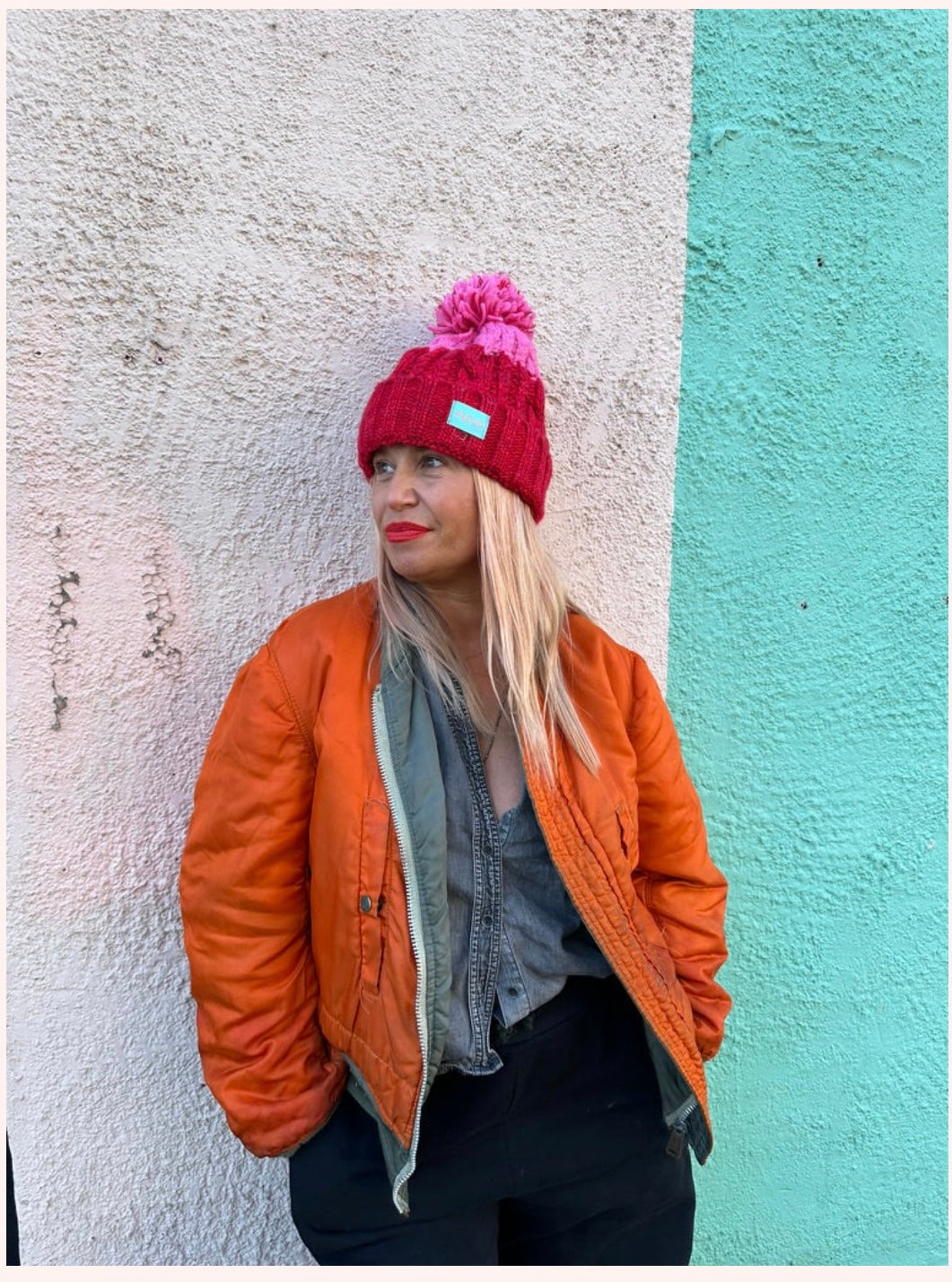 Silky lined pom pom hat in red and pink with proud logo
